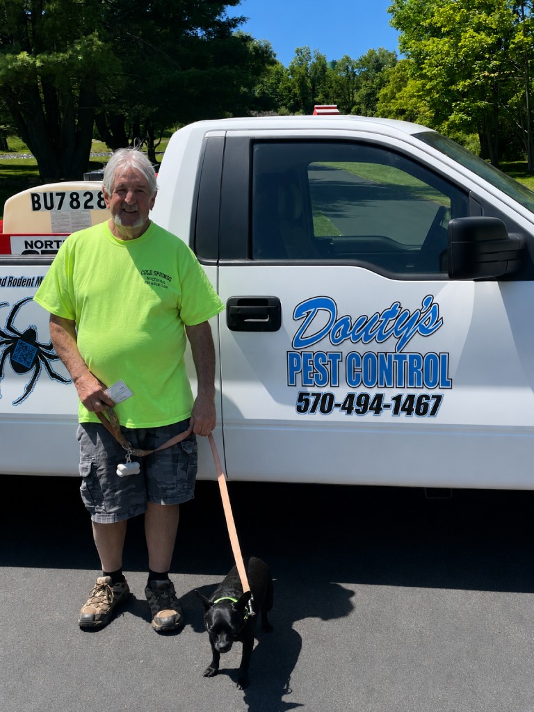 A customer and his dog in front of a Douty's Pest Control truck