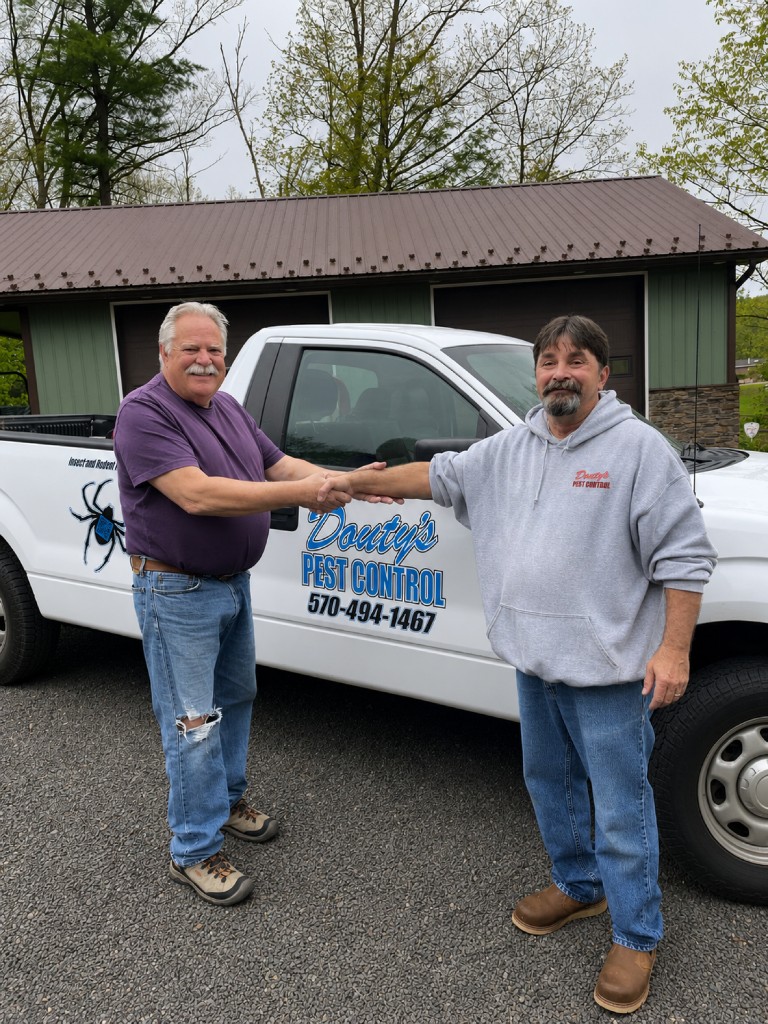 Douty's technician shaking hands with a customer in front of a service truck