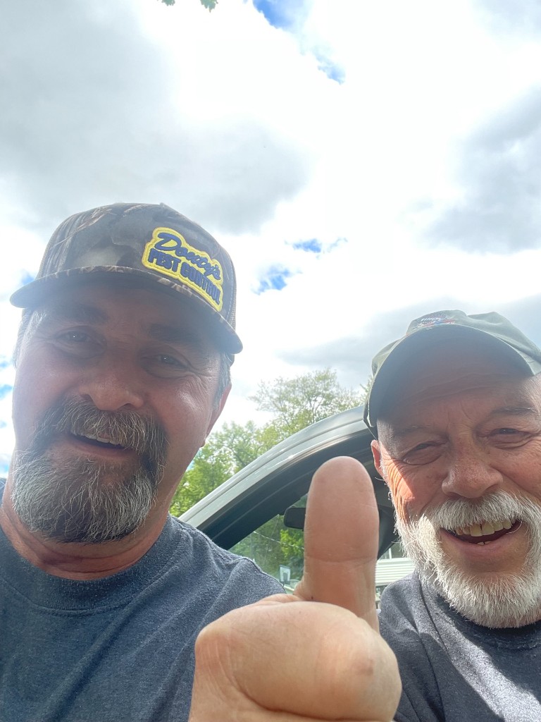 Douty's Pest Control tech with a customer, thumbs-up in front of a service truck